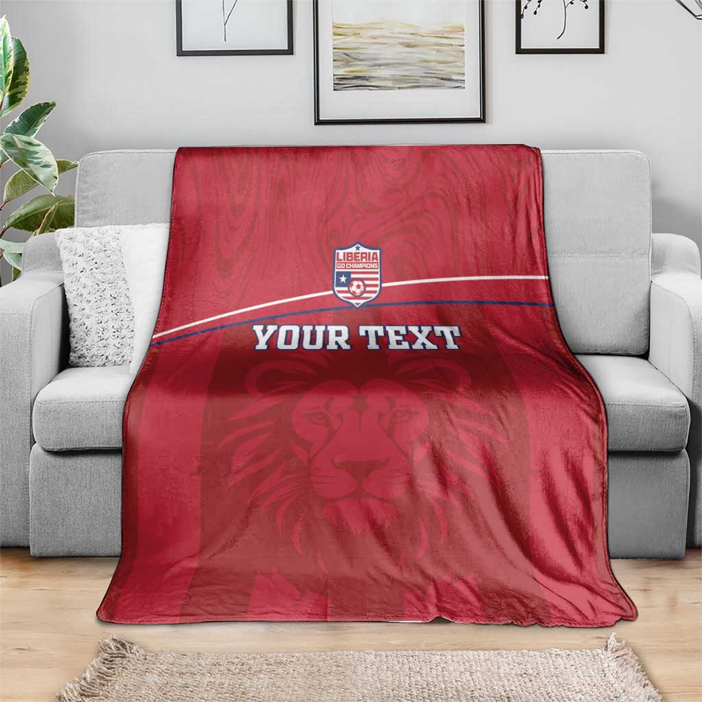 Red lion-motif blanket with Liberia crest and custom text stripe on sofa