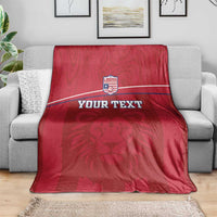 Red lion-motif blanket with Liberia crest and custom text stripe on sofa