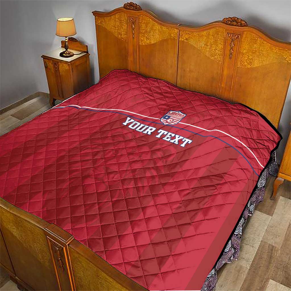 Red quilted football blanket on bed with Liberia crest and 'YOUR TEXT' center.