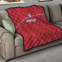 Red quilted football blanket draped on sofa with Liberia crest and 'YOUR TEXT' stripe.