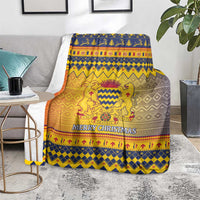 Christmas throw blanket on a sofa with blue, gold, orange, and gray “Merry Christmas”