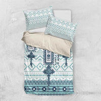 Folded teal and white bedding set featuring geometric cross design and matching pillow shams