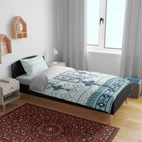 Teal and white cross geometric duvet cover laid on a bed with pillow shams
