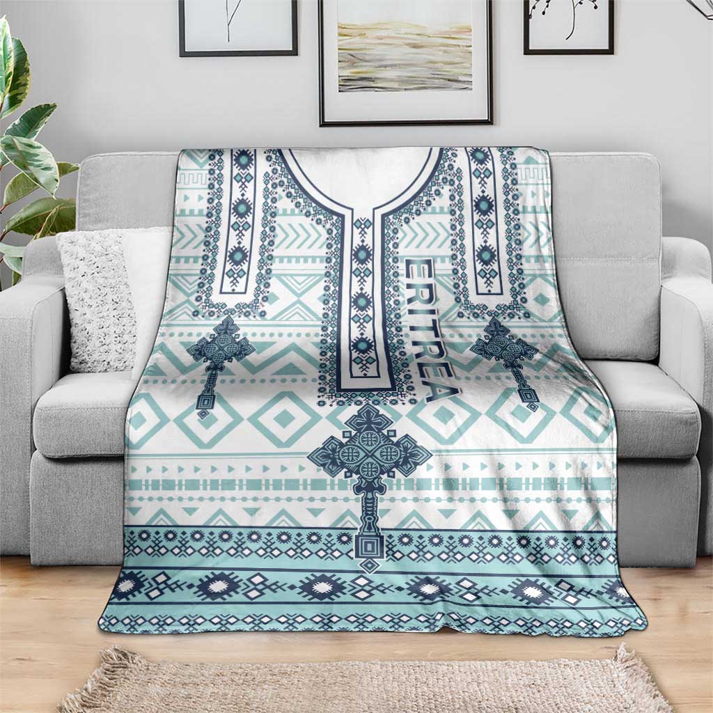 Geometric cross print blanket in teal, navy, and white, laid over gray sofa