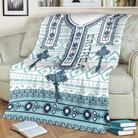 Teal and navy geometric cross pattern blanket, white top border, draped on armchair