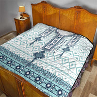 Bed quilt with white and aqua cross-pattern design and dark blue border on top