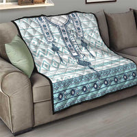Quilt folded on a sofa, white and aqua with dark blue geometric stripe and medallion