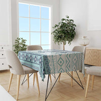 Teal and navy patterned tablecloth covering a dining table with repeating cross design