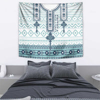 Eritrean cross tile tapestry with teal and dark-blue trim patterns, laid over bed