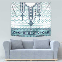 Eritrean cross tile tapestry with teal and blue ornamental borders, displayed above sofa