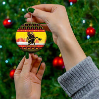 Yellow round ceramic Christmas ornament with Krampus artwork, held with gold hanging string.