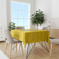 Yellow tablecloth with blue crest design draped over rectangular dining table