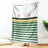 Rugby blanket draped vertically: white, green horizontal stripes, colorful border, logos