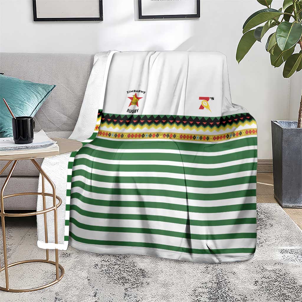 Rugby blanket in gray room: white with green stripes, colorful border band, logos