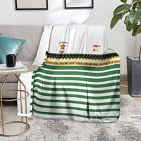 Rugby blanket in gray room: white with green stripes, colorful border band, logos