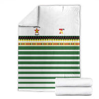 White rugby blanket with green stripes, colorful patterned band, folded for storage, logos