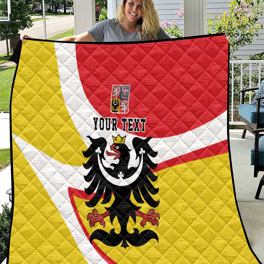 Quilt blanket outdoors with yellow, white, and red diagonal stripes and black eagle design