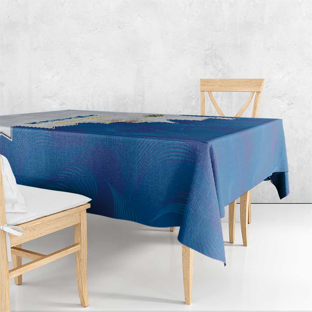 Blue tablecloth with coat of arms motif and zigzag border, over wooden dining table