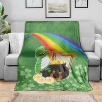 Green throw blanket on sofa with harp, pot of gold, rainbow stripe and clover pattern