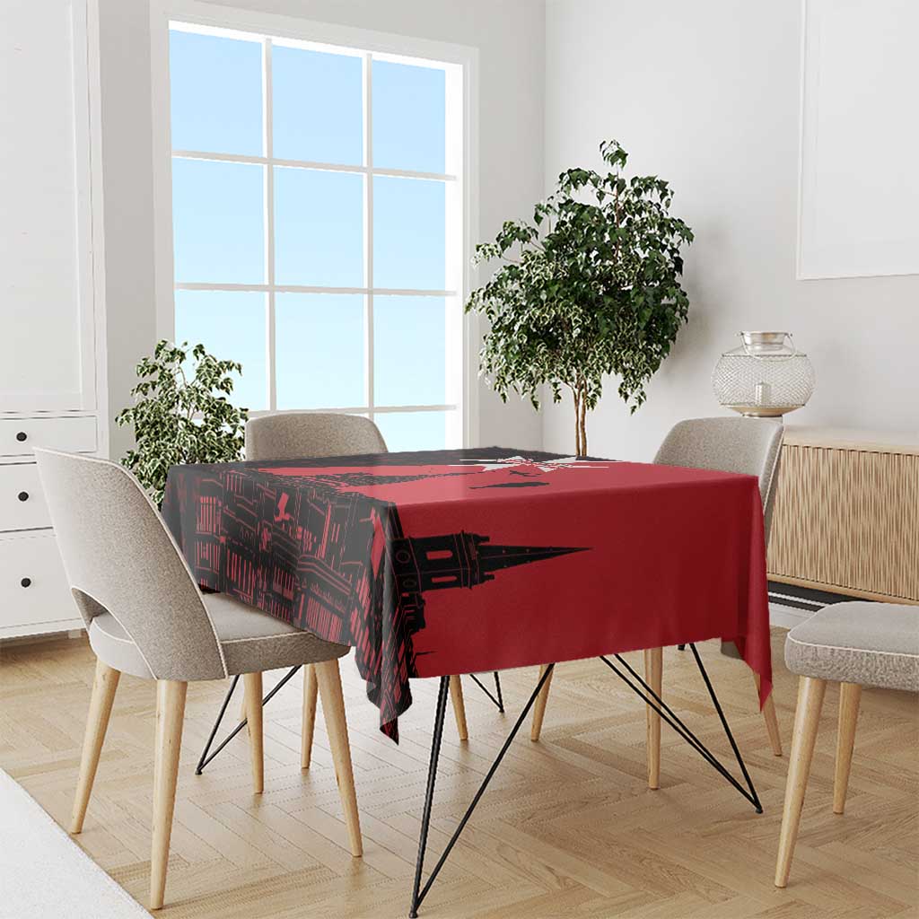 Red tablecloth with black Malta-themed city print, draped over dining table