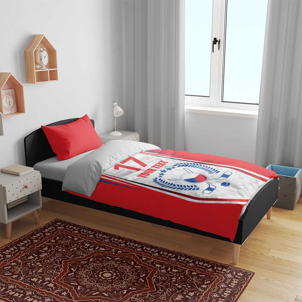 Red comforter bedding on a bed with Czech-style crest, “17” and “YOUR TEXT,” two red pillows