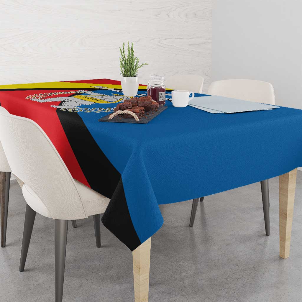 Tablecloth with red, blue, and yellow diagonal stripe design and central emblem.