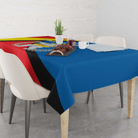 Tablecloth with red, blue, and yellow diagonal stripe design and central emblem.