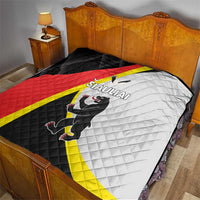 Quilt laid on bed with black, red, white and yellow panels and SIAULIAI crest