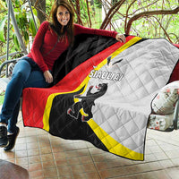 Quilt held outdoors with black, red, white and yellow panels and SIAULIAI crest