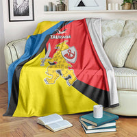 Taurage blanket with yellow, blue, and red stripes, crest graphic, and TAURAGE text