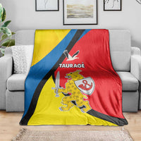Yellow, blue and red Taurage blanket draped over a sofa with crest and TAURAGE text