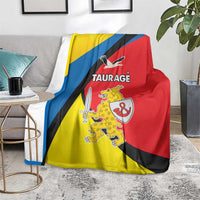 Taurage blanket on a gray couch, yellow-blue-red design with crest and TAURAGE text