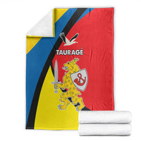 Folded Taurage blanket with yellow, blue, and red flag design, crest and TAURAGE text