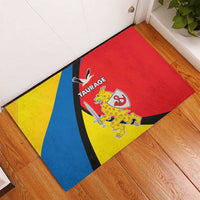 Red rubber doormat with blue and yellow diagonal stripes and Taurage crest graphic
