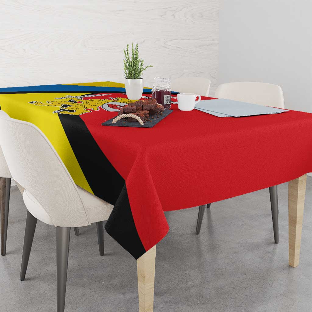 Red tablecloth with yellow, blue and black diagonal pattern and crest emblem.