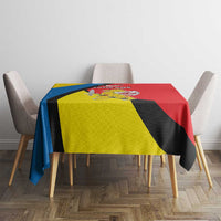 Yellow, blue, black and red geometric patterned tablecloth draped over table.