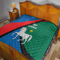 Quilt blanket on bed, blue red green panels with black stripe and white horse Utena logo