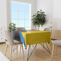 Multicolor tablecloth with yellow base and blue stripe over the table, matching edge trim