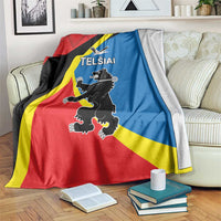 Red, black, yellow, and blue flag-themed blanket draped over sofa with emblem and text