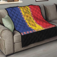 Quilt draped on a gray sofa with blue, yellow, and red embroidered center and black edge