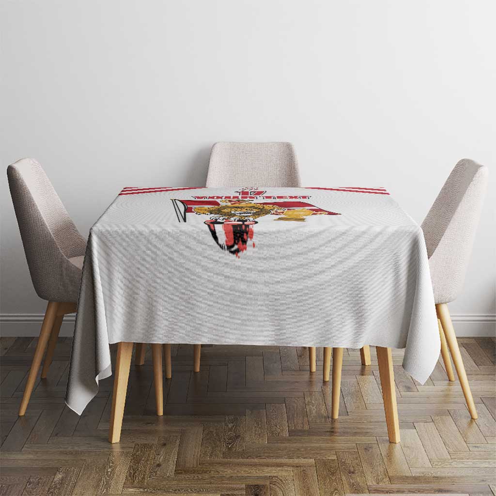 White tablecloth with central football-themed print and red stripe border, on dining table