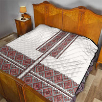 White quilt with red folk embroidery border, diamond quilting, laid on a bed