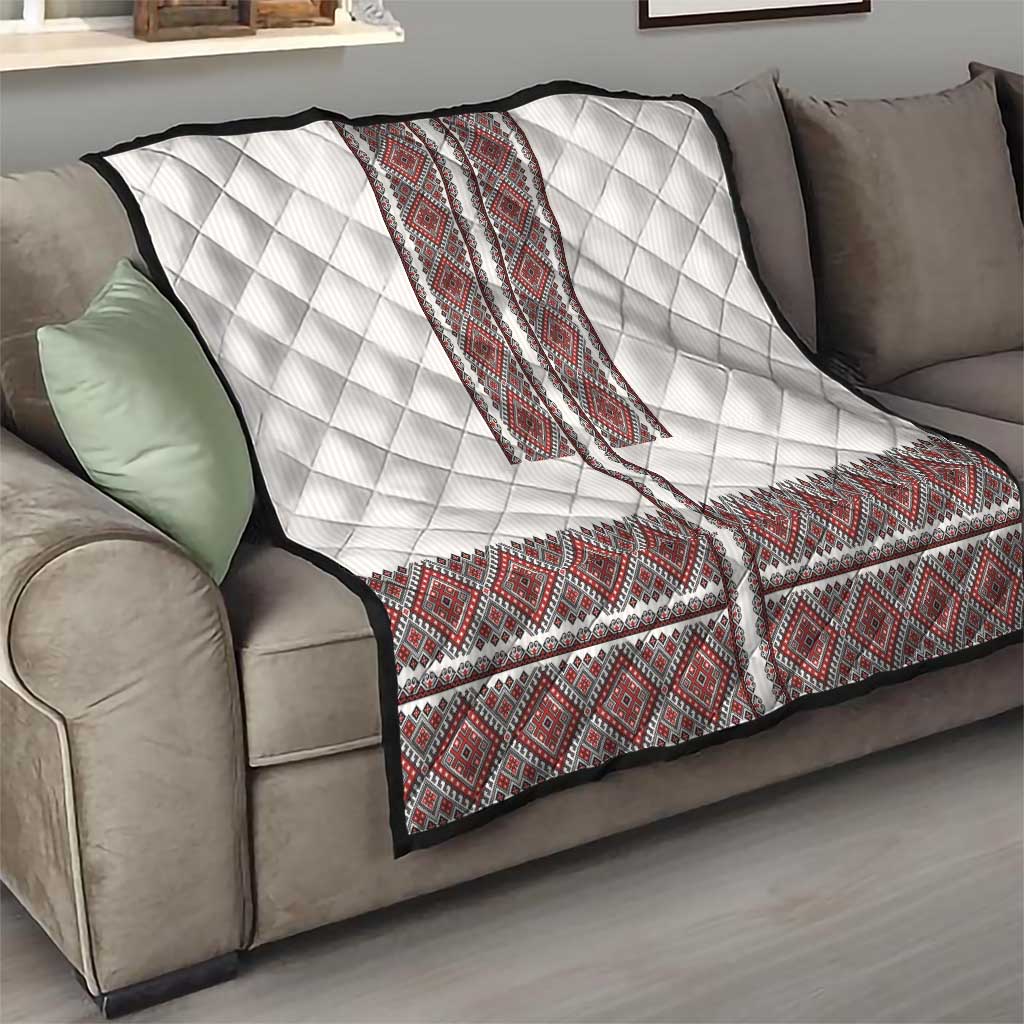 White quilt with red folk embroidery V-styled panel and diamond quilting, on a sofa