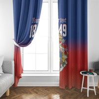Blue and red window curtain panels with crest graphic, hanging over a bright window