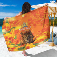 Orange sarong with lion-and-tulip print and centered 'Your text'.