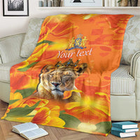 Orange personalized blanket with lion face, crown emblem, and tulip pattern on couch