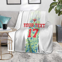 Custom football blanket on floor, white with number 17 graphic and red “YOUR TEXT”