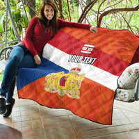 Orange quilt flag laid on a sofa: blue and white stripes, crest emblem, “YOUR TEXT”