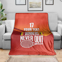 Red tennis blanket on a sofa with 'WINNERS NEVER QUIT' and number 17 design