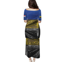 Back view of blue long dress with short sleeves, flag-style print in yellow and black